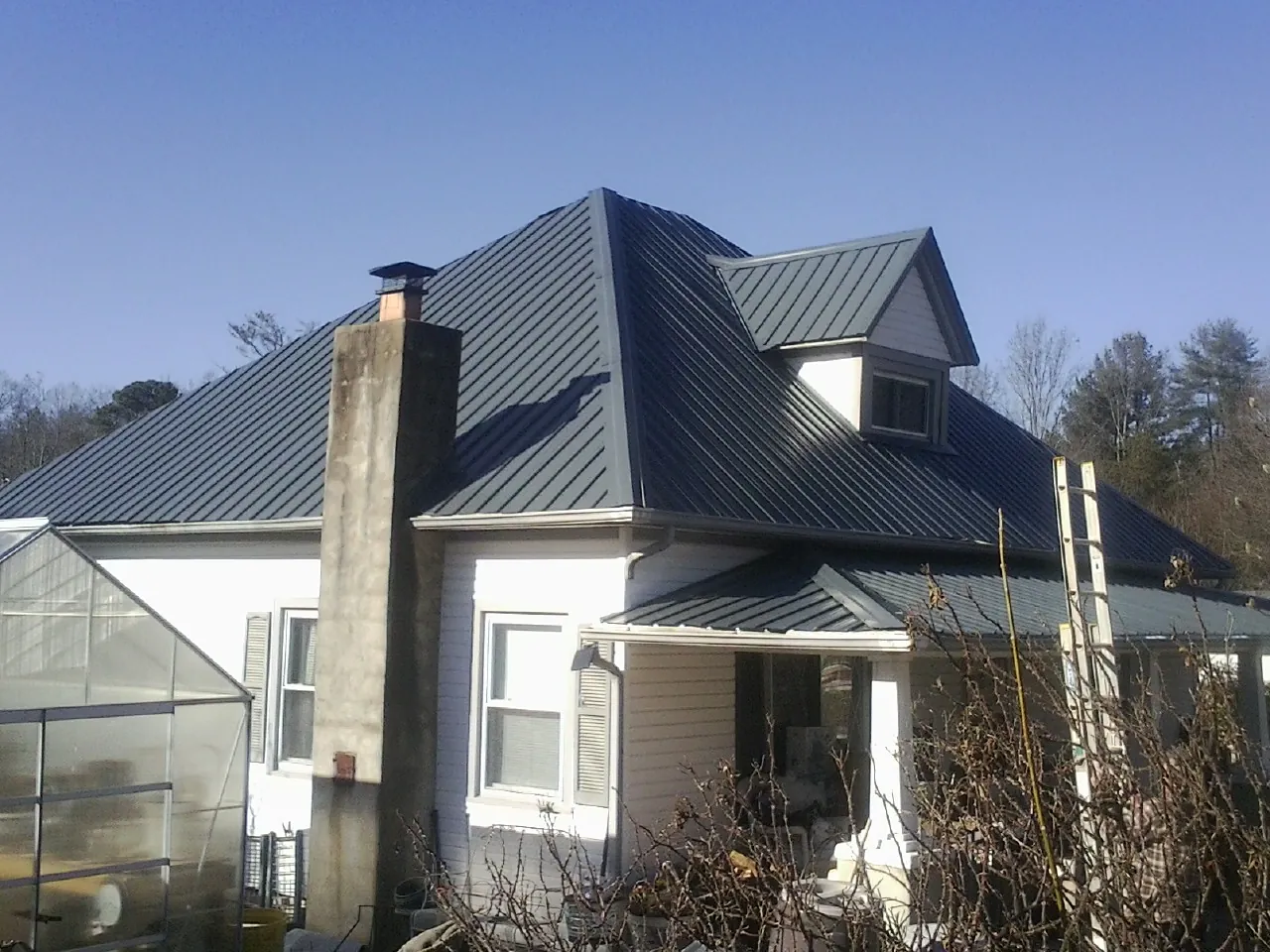 Dark blue standing seam metal roof on a white farmhouse with dormer — Slate & Tile Roof Repair by Roofing Brothers in Eufaula