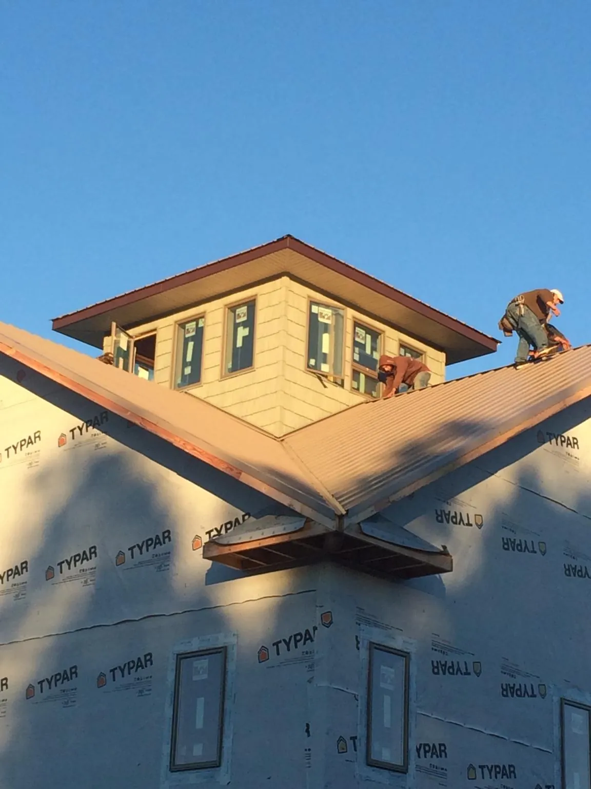 Roofers working around a rooftop cupola on a new metal roof at sunset — Roof Waterproofing in Eufaula by Roofing Brothers